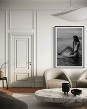 Load image into Gallery viewer, A sophisticated living room featuring the framed photography 'Riding Tide', depicting a woman in a white swimsuit enjoying the ocean on her surfboard, adding a beachy ambiance to the space.