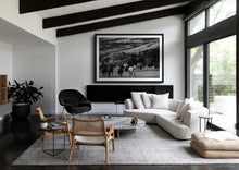 Load image into Gallery viewer, A chic interior featuring a modern living room with a large framed black and white piece of Western Art depicting a herd of horses in Patagonia, complementing the stylish decor and creating an elegant atmosphere.
