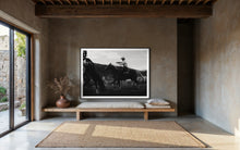 Load image into Gallery viewer, Black and white fine art photography titled &#39;Gallant Gallup&#39; by Addison Jones Studio, showcasing a cowboy skillfully riding a horse at a rodeo in a rustic interior setting.
