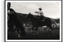 Load image into Gallery viewer, Close-up view of &#39;Gallant Gallup&#39; by Addison Jones Studio, depicting a cowboy in motion on horseback during a rodeo, framed in classic black.

